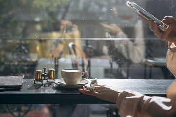 Fototapeta na wymiar Attractive smiling girl taking photo cup of latte, using smartphone
