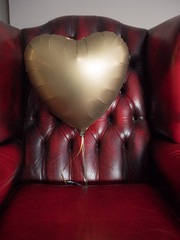 Antique sofa with red leather upholstery with a heart-shaped balloon