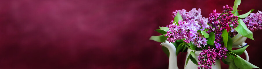A bouquet of lilacs in an old white coffee pot against a purple background. bright colors of...