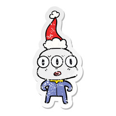 distressed sticker cartoon of a three eyed alien wearing santa hat