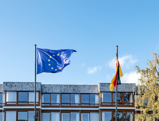 waving European Union blue flag and German flags in front of Federal Constitutional Court building...