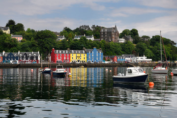 Colorful houses reflected in the water of Tobermory harbour on the Isle of Mull with moored boats Scottish Inner Hebrides Scotland UK