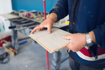 Professional carpenter holding laminate flooring boards midsection