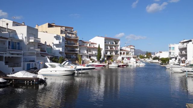 Beautiful panorama of the houses and hotels on the shores of the picturesque Mediterranean canal in the Golf de Roses against the backdrop of mountains and blue sky