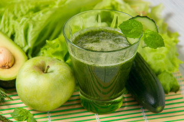 Healthy green smoothie with ingredients on wooden background
