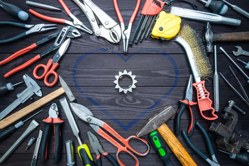 Tool and heart on dark wooden background. Love for your work, Father's Day.