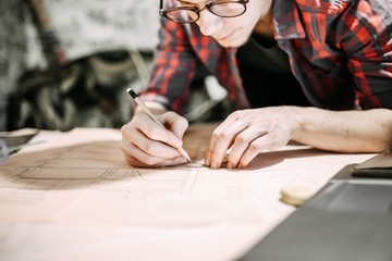 Obraz premium engineer, designer, architect draws a project with glasses. Concentrated work of a specialist.