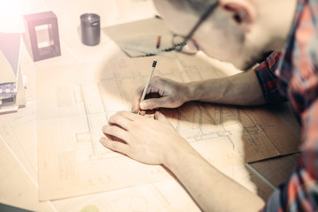 engineer, designer, architect draws a project with glasses. Concentrated work of a specialist.