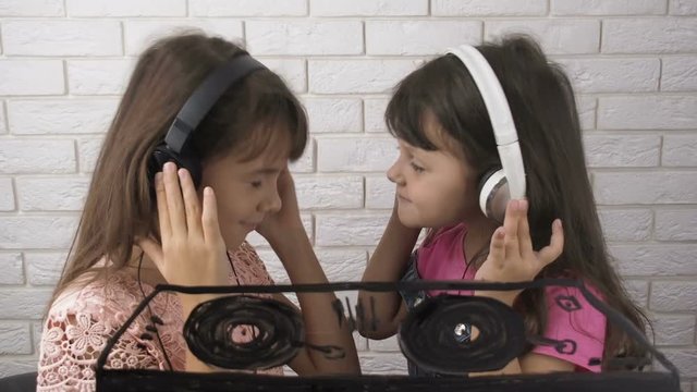 Children dancing with headphones. Happy little girls listen to music with headphones.