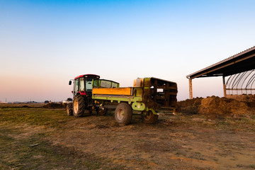 夕日の中のトラクターに取り付けられた堆肥散布機マニアスプレッダ