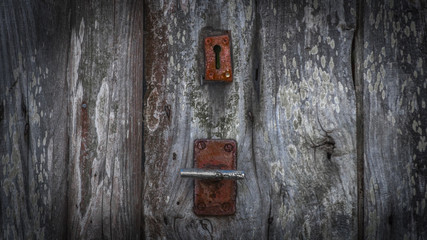 Cerradura antigua oxidada vintage en puerta de madera centenaria.