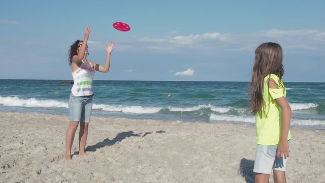 Family spending time on beach. Fun with mom on vacation. Mother and daughter play frisbee on the beach.