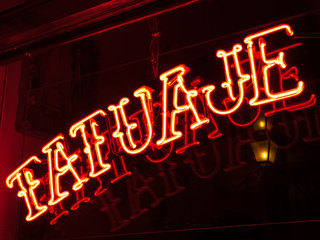 Cartel luminoso de neón rojo de tatuajes y piercings