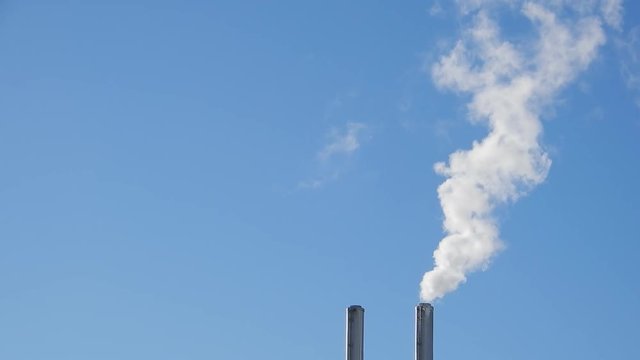 Top Of Two Smoke Stacks Industry Blowing White Smoke With Clear Blue Background