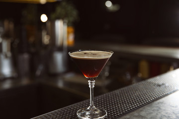 Glass of martini espresso cocktail on bar counter, closeup. Space for text