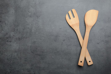 Wooden spatula and fork on grey background, top view with space for text