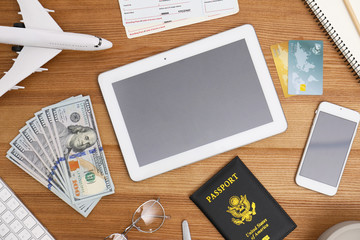 Flat lay composition with airplane model and tablet on wooden table in travel agency