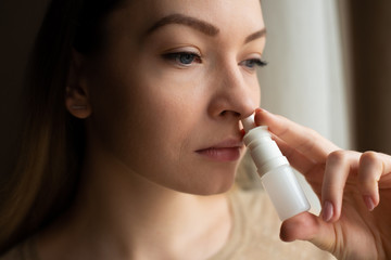 The girl uses spray on a dark background. Medicine and treatment