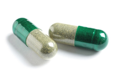 Green spirulina capsules on white background. Alternative medicine