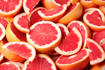 Many sliced fresh ripe grapefruits as background, closeup