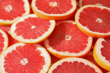 Many sliced fresh ripe grapefruits as background, closeup