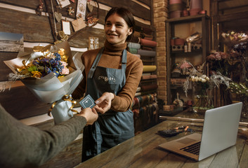 Happy woman gardener in the flower shop make bouquets for a holiday. Flower's business. Lifestyle flower shop. Girl create a beautiful flower composition for sale.