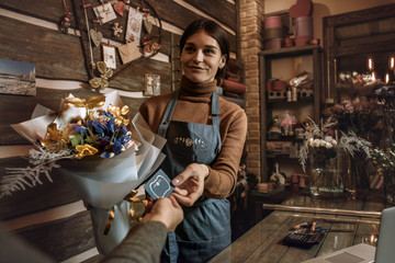 Fototapeta na wymiar Happy woman gardener in the flower shop make bouquets for a holiday. Flower's business. Lifestyle flower shop. Girl create a beautiful flower composition for sale.
