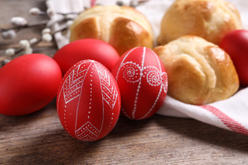Red painted Easter eggs and buns on wooden table, closeup