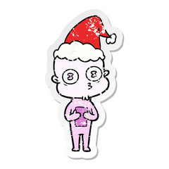 distressed sticker cartoon of a weird bald spaceman wearing santa hat