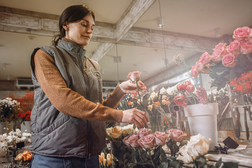 Woman - gardener in the flower shop make bouquet for a holiday. Family flower's business. Lifestyle flower shop. Beautiful flower composition. Love to flower's.Sunlight. Detail. Close up.