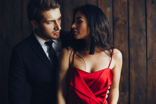 Elegant man in a black suit. Couple at home. Hot woman in a red dress