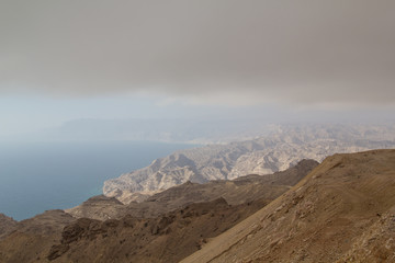 The summits of the Dhofar mountains are covered in grey, thick and heavy clouds, cold and humidity while the coastal region of the Sultanate of Oman is flooded by sunlight and warmth 