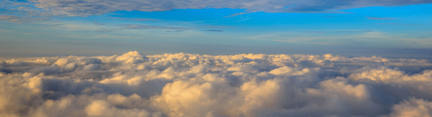 Abstract photograph above the clouds, sea of clouds effect, flying through the sky, aerial view, white puffy clouds and blue sky. Low pressure front atmospheric effect, cloudscape, clear weather.