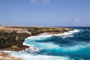 Fototapeta na wymiar Wild and high waves breaking at the rough shoreline of the east coast of the island of Bonaire