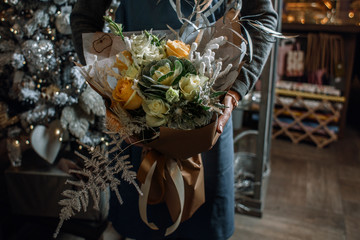 Gardener's in the flower shop make bouquet for a holiday. Family flower's business.  Lifestyle flower shop. Beautiful flower composition. Flower's bouquet in the women's hands.Detail. Close up.