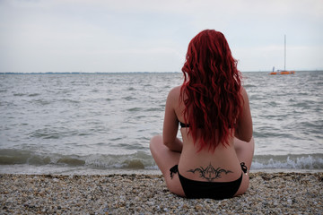 Frau sitzt an einem Strand und kehrt in sich