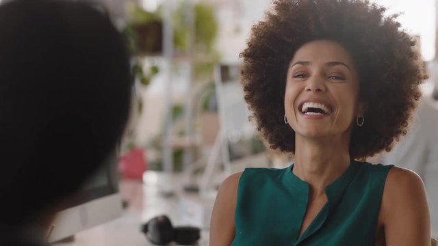 young mixed race business woman with afro chatting to intern discussing job interview colleagues having conversation in office enjoying teamwork