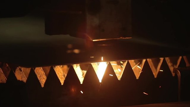 Modern programmed robot head cuts metal with sparks.