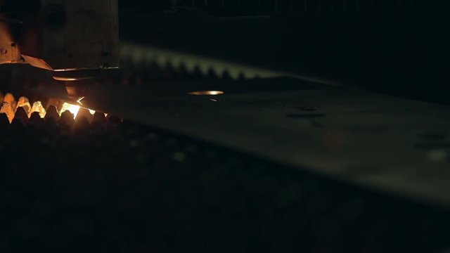 Modern programmed robot head cuts metal with sparks.