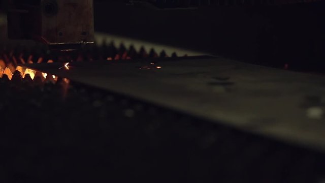 Modern programmed robot head cuts metal with sparks.