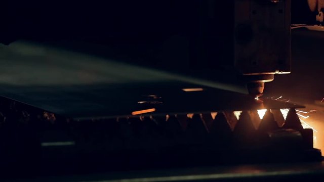 Modern programmed robot head cuts metal with sparks.