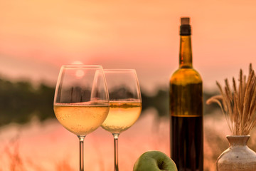 A romantic dinner in summer on a beach at sunset with two glasses of white wine