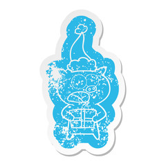 cartoon distressed sticker of a pig with christmas present wearing santa hat