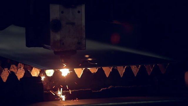 Modern programmed robot head cuts metal with sparks.