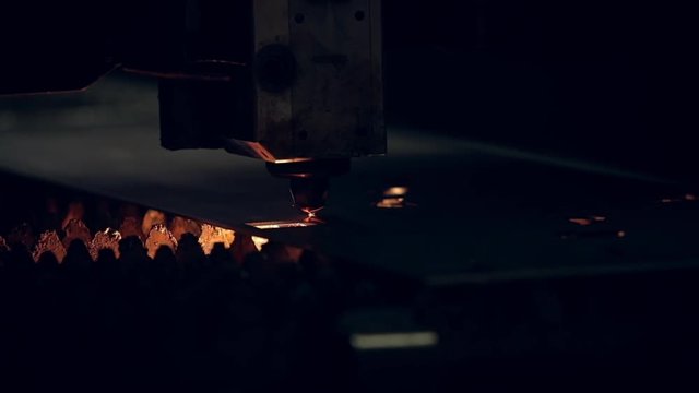 Modern programmed robot head cuts metal with sparks.