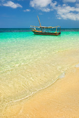 Fototapeta premium sea water with golden sand and boat under sky in Tanzania