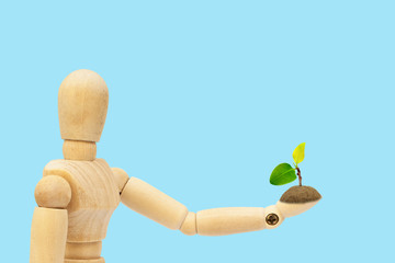 Ecology Concept : Wooden figure mannequin holding green sprout tree in hand.