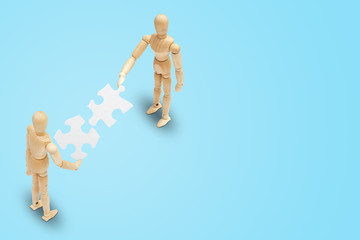 Business Teamwork Concept : Two wooden figure mannequin holding and connecting white paper puzzle piece together.