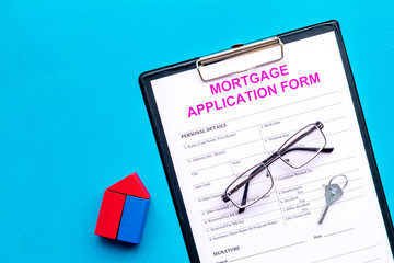 Mortgage concept. Mortgage application form near key and house made of constructor on blue background top view space for text