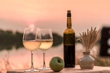 A romantic dinner in summer on a beach at sunset with two glasses of white wine